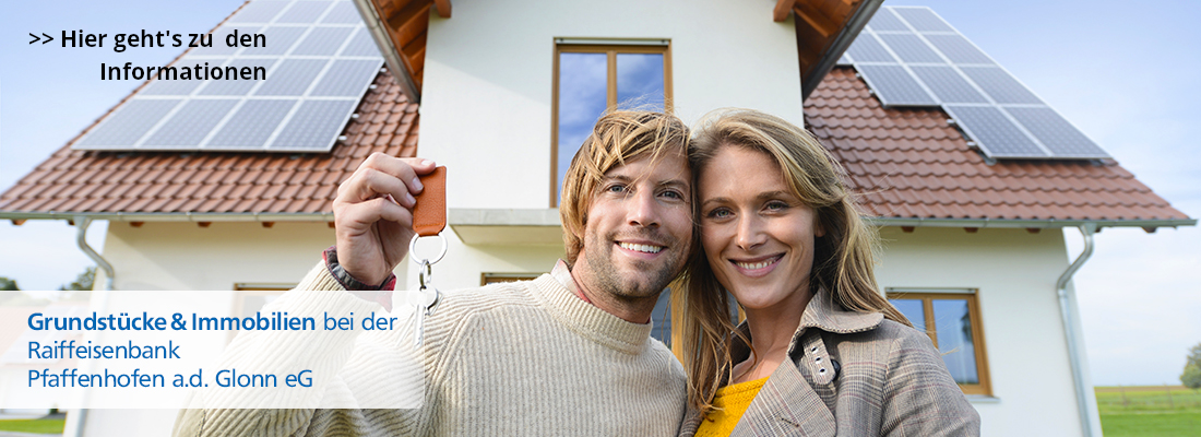 Junges Paar vor Haus mit Schlüssel in der Hand, Text: Grundstücke und Immobilien bei der Raiffeisenbank Pfaffenhofen a.d. Glonn eG